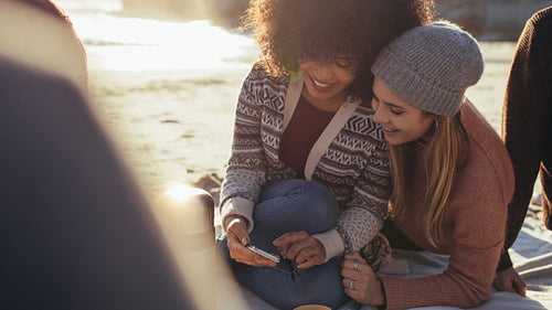 Friends enjoying a beach party with phone