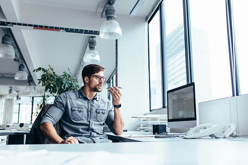 Young businessman talking on mobile phone in office