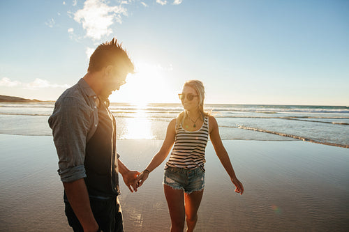Romantic couple holding hands and walking on beach