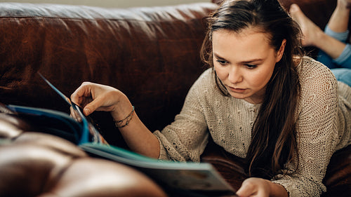 Young woman relaxing at home reading a book 