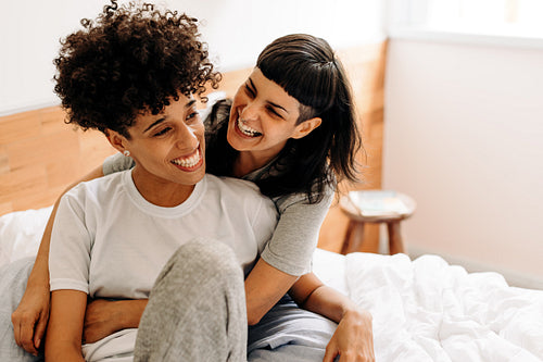 Lesbian couple laughing cheerfully at home