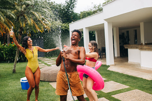 Friends celebrate summer water fight by pool