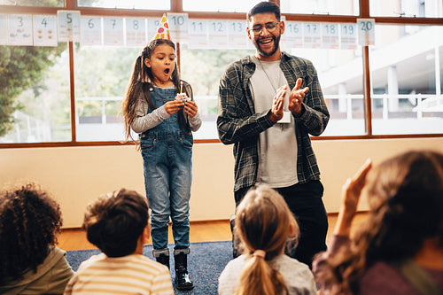 Female students blows a candle on her birthday. Party celebration in primary school