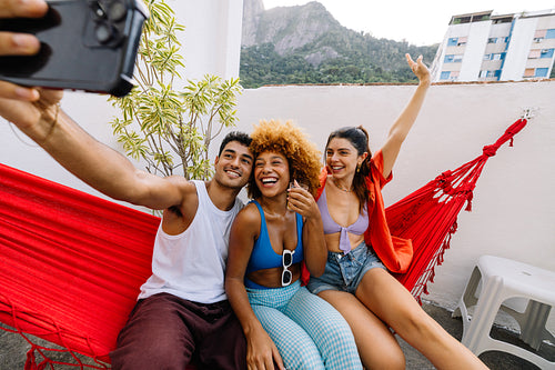 Brazilian friends enjoying rooftop drinks and taking a lively selfie