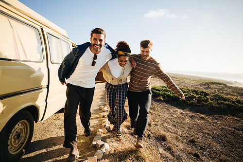 Friends walk along a coastal trail beside a yellow van at sunset
