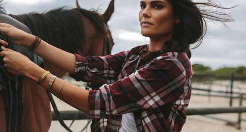 Female rider getting horse ready for ride