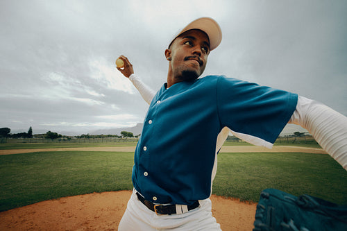 Male baseball pitcher in action during a league game, preparing to throw a powerful pitch
