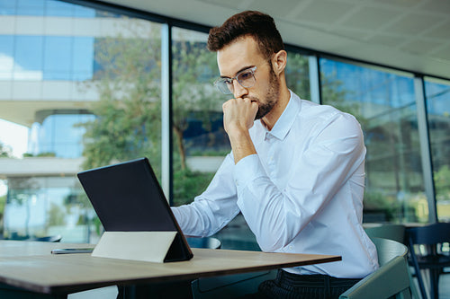 Concerned businessman working on a tablet in a modern office setting