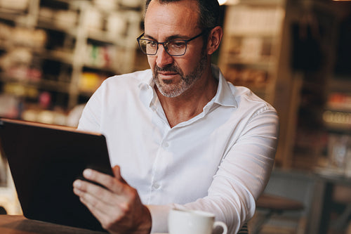 Businessman working on his digital tablet at coffee shop