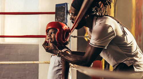 Kid wearing boxing head guard standing inside a boxing ring