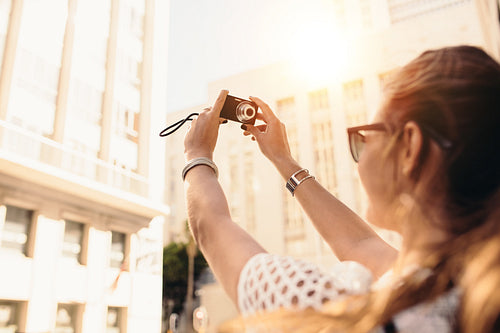 Young tourist recording selfie in a street surrounded by buildings.