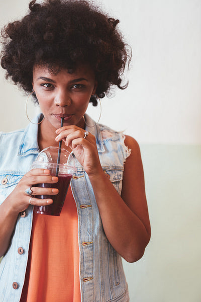 Young african woman drinking fresh fruit juice