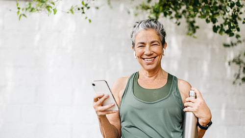 Motivated senior woman browsing some music for her outdoor workout routine