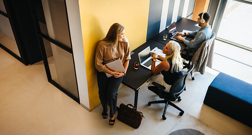 Three professionals working and discussing ideas in a modern creative office setting