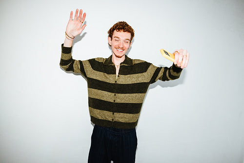 A playful young man poses in the studio with a smartphone