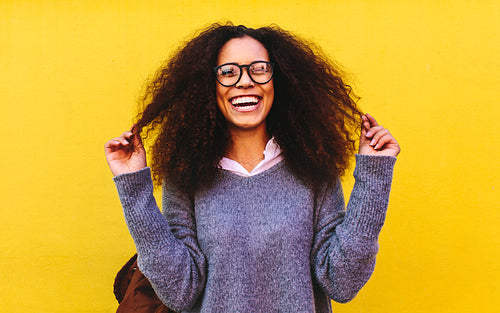 Laughing curly haired woman on yellow background