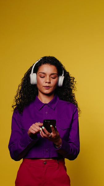 Young woman dances and enjoys music on her phone with headphones