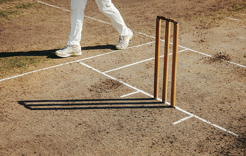 Cricket ground with wickets and player's shoes captured during a gameplay moment