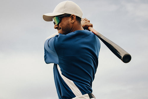 Male amateur baseball player taking a powerful practice swing with his bat