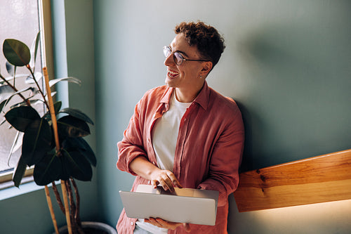 Smiling young adult working on a laptop in a modern interior setting
