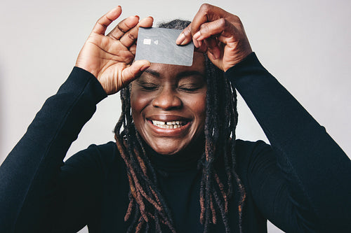 Mature woman smiling happily while holding up a credit card