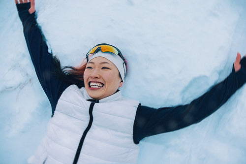 Joyful woman lies in snow celebrating winter recreation