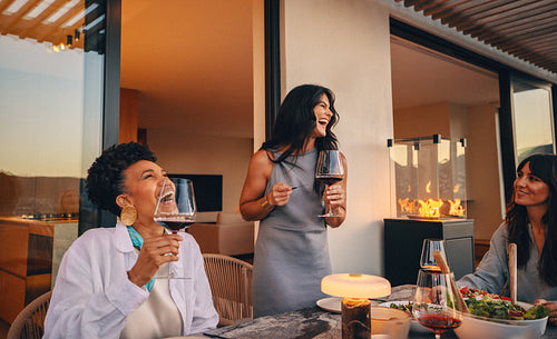 Group of women enjoying wine and a meal on a patio evening