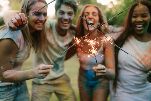 Friends burning fire sparkle sticks standing outdoors in a park