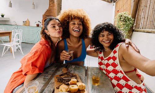 Three women smiling and posing for a photo together at outdoor table