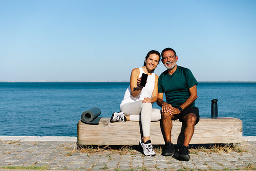 Smiling middle-aged couple enjoying outdoor relaxation by the water during a break
