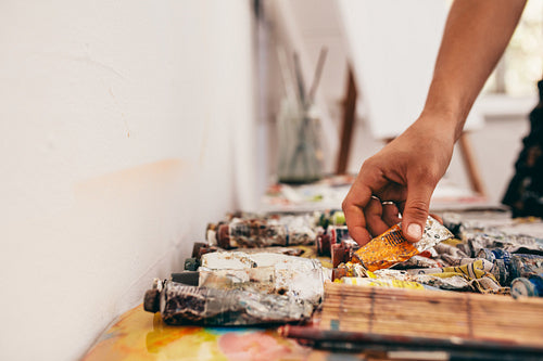 Artist hand picking up color tubes from the table