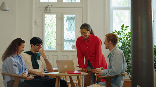 Coworker joins as team celebrates progress during a business meeting in a cafe office