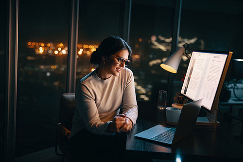 Happy businesswoman using a laptop to engage in an online meeting at night
