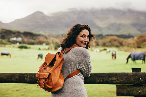 Woman standing by ranch fence