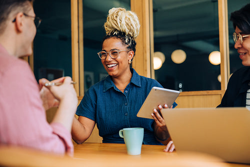 Three coworkers having a cheerful discussion at a modern office table