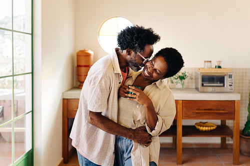 Loving couple hugging in the kitchen, sharing a warm cheek kiss