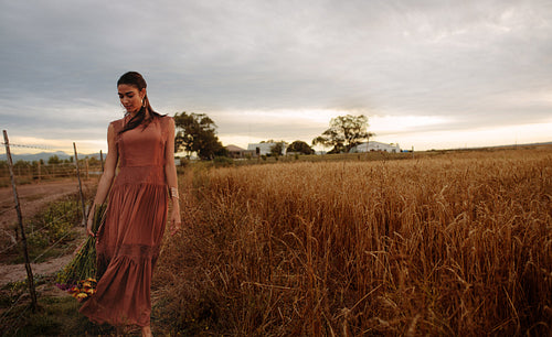Woman strolling on wheat field with flowers