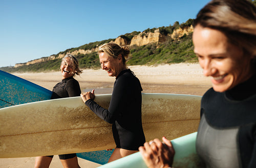 Mature women enjoying surfing at a sunny beach with smiles and laughter