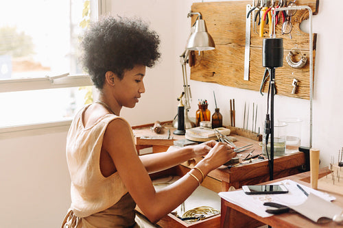 Woman making handmade jewelry in her workshop