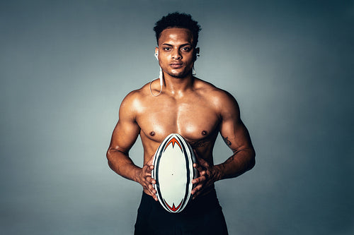 Fit young man holding rugby ball