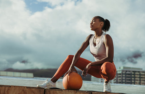 Fitness woman relaxing with ball on rooftop