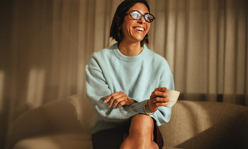 Woman enjoys a coffee break on the couch at home during work