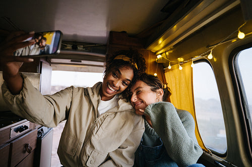 Friends take a fun selfie inside a cozy camper van