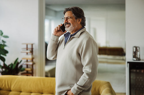 Senior man talks on a smartphone at home