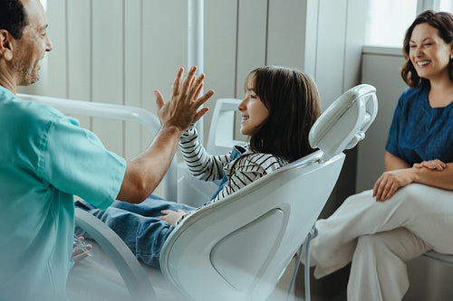 Celebrating with a high five at a family dental clinic visit after check-up