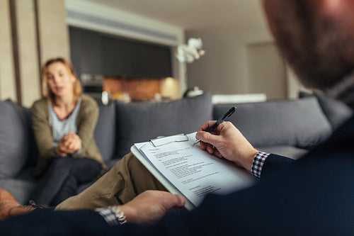 Psychologist writing notes during a therapy session with patient