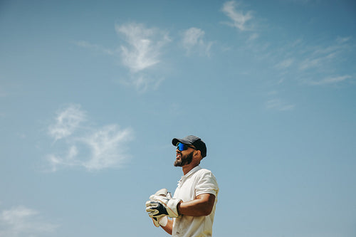 Wicket keeper standing against a blue sky background during a cricket match