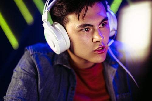 Tense video gamer looking at the computer screen as he plays a game with a headset on