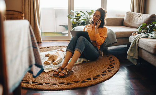 Mother working from home on laptop and phone beside baby