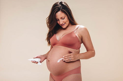 Mom-to-be's prenatal skincare routine: Woman applying belly balm for a happy pregnancy